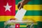 Togo flag, hand dropping ballot card into a box - voting, election concept