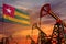 Togo oil industry concept. Industrial illustration - Togo flag and oil wells with the red and blue sunset or sunrise sky