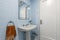 Toilet with blue square tiled walls, white wooden door and white toilet