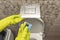 Toilet cubes cleaner in hand. A hand lowers a disinfectant cube into the water of a toilet bowl built into the wall