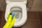 Toilet cubes cleaner in hand. A hand lowers a disinfectant cube into the water of a toilet bowl built into the wall