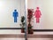 Toilet entrance with restroom sign with blue silhouette man symbol and red silhouette woman symbol