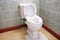 Toilet with height extension for disabled senior person indoors in house