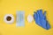 Toilet paper, soap, medical mask, blue rubber gloves shot from above close-up on a yellow background. Sanitation. Medicine.