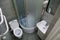 Toilet room interior with white toilet bowl, shower cabin and grey wall tiles