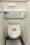 The toilet seat with the lid closed at a aircraft lavatory. With a tissue dispenser on top