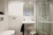 Toilet with shower and glass partition, white sink, wicker laundry basket