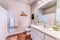 Toilet beside vanity unit with sink mirror and white cabinets inside bathroom