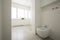 Toilet in white spacious bathroom interior with windows. Real ph