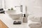 Toiletries and stylish vessel sink on light countertop in modern bathroom