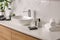 Toiletries and stylish vessel sink on light countertop in modern bathroom