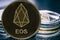 Token cryptocurrency EOS on the background of a stack of coins.