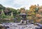 Tokyo Metropolitan Park KyuFurukawa japanese garden`s Yukimi stone lantern overlooking by red maple momiji leaves in autumn