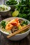 Tom Kha goong soup - coconut shrimp soup with noodles and shiitake mushrooms on wooden table