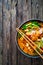 Tom Yum - Thai soup with halibut nuggets and rice noodles on wooden table