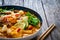 Tom Yum - Thai soup with halibut nuggets and rice noodles on wooden table