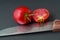 Tomato closeup with knife and water droplets on black background
