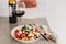 Tomato crostini salad with mozzarella cheese. Refreshing healthy dinner. Glass of red wine. Nourishing salad lunch. Panzanella