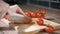 Tomato cutting closeup. Chef slices the cherry tomato. Knife, cutting Board, cherry tomato. The hands of the cook.