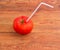 Tomato with drinking straw on the old planks