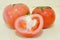 Tomato fruit with half cross section isolated on wooden background