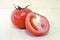 Tomato fruit with half cross section isolated on wooden background