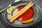 Tomato gazpacho, traditional Spanish cold soup or appetizer in a dark clay bowl on a stone board