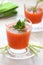 Tomato juice with parsley and celery greens in a glass on a saucer, with a green napkin, with a blurry background