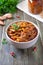 Tomato lobio of green bean pods in a bowl on a wooden background. Lenten dish