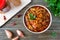 Tomato lobio of green bean pods in a bowl on a wooden background.   Lenten dish. Flat lay, top view