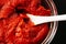 Tomato paste in a glass bowl with a white spoon for pizza sauce