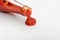 Tomato sauce is poured from the glass bottle on white background