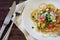 tomato sauce whole wheat spaghetti pasta with fresh, fried scallions and parmesan served on a white plate on a dark rustic wooden