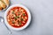Tomato soup. Minestrone soup. Tomato bean and pasta soup bowl with toasts on gray stone background