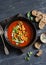 Tomato soup with spicy fried chickpeas on a dark wooden table, top view.