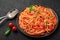 Tomato spaghetti on black plate on dark slate table. Tomato sauce pasta is classic italian cuisine dish. italian food
