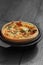 Tomato and spring onion quiche in a cast iron pot dish on wood