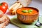 Tomatoe soup with bread sticks and basil on wooden background