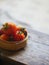 Tomatoes in a bamboo basket on a wooden table.