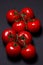 Tomatoes on a black background. Tomatoes on a vine on a dark background.