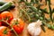 Tomatoes on branch with zucchini, head of garlic and rosemary twig with green olives on branch over a used oak wood table