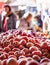 Tomatoes closeup in a market stall with some persons background. Fruits and vegetables market. People buying and enjoying the