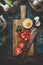 Tomatoes and eggs on wooden cutting board with knife on dark rustic kitchen table background. Shakshuka cooking ingredients. Top
