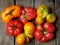 Tomatoes irregular shape of different varieties and colors on wooden background.