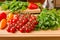 Tomatoes, mini bell peppers and parsley on wooden cutting board.