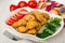 Tomatoes, napkin, partitioned dish with patties, parsley, slices of tomato, fork on wooden table