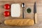 Tomatoes, plastic jar with creamy cheese, spoon, bowl with dill, knife, loaf of bread on table. Top view