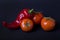 Tomatoes and red pepper on a dark background. Composition of red peppers and tomatoes on a black background