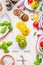 Tomatoes salad making. Green,yellow and red ripe tomatoes on white marble cutting board and white wooden background with ingredie