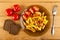 Tomatoes in saucer, slices of bread, pieces of tomatoes and slices of fried potatoes in brown plate, fork on wooden table. Top